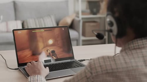 Person Playing Video Game on Laptop at Home