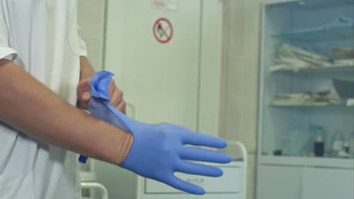 Doctor Putting on Surgical Gloves in Hospital Setting