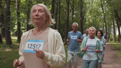 Aged Caucasian Woman Running in Park with Teammates