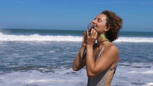 Young Woman Walking on the Beach By the Ocean Takes Off Her Protective Face Mask and Spreads Her