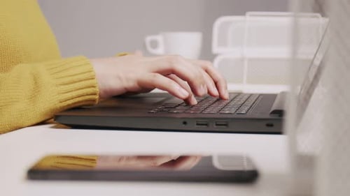 Woman with Headphones Types at Laptop on Desk
