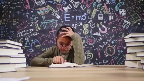 Front view of Asian girl reading book in working room at home