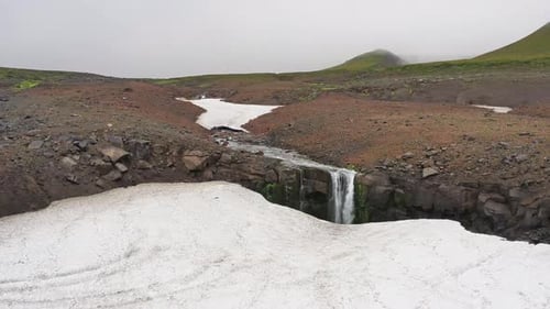 Wasserfall und Schnee in den Bergen