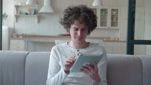 Young Adult Using Tablet Device At Home