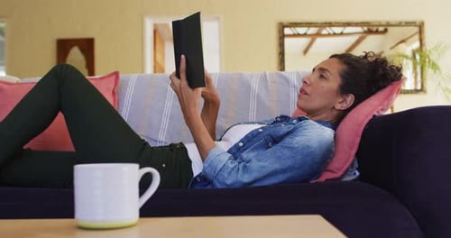 Woman Reading a Book Relaxing on Couch