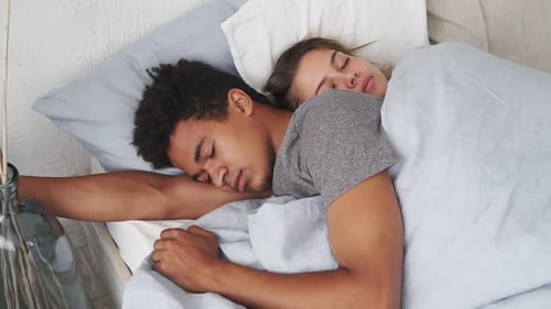 Nahaufnahme eines gemischtrassigen Paares, das im Bett liegt und schläft, während es sich umarmt