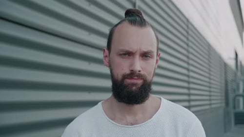 Bearded Man with Bun Looks at Camera