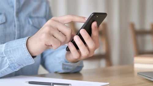 Man Uses Smartphone at Desk in Office