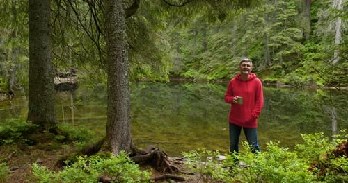 Bearded Man with a Mug Near a Mountain Lake