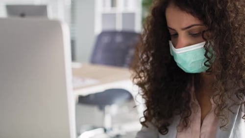 Video of woman in protective mask working in the office. Shot with RED helium camera in 8K