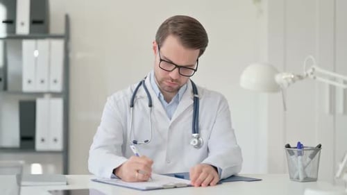 Concentrated Doctor Writing on Medical Chart in Office