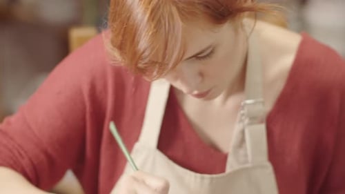 Woman Paints Ceramic Bowl in Brightly Lit Studio