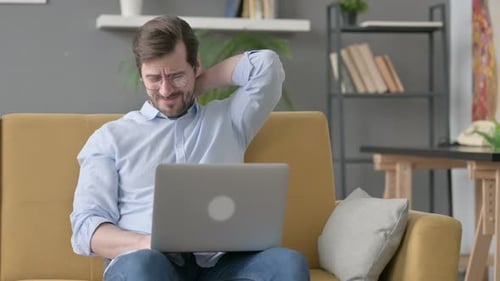 Man Working on Laptop with Neck Pain on Couch