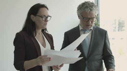 Grey Haired Male Executive Giving Documents To Female Assistant