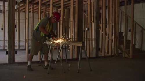 Construction Worker Cuts Metal with Power Tool Indoors