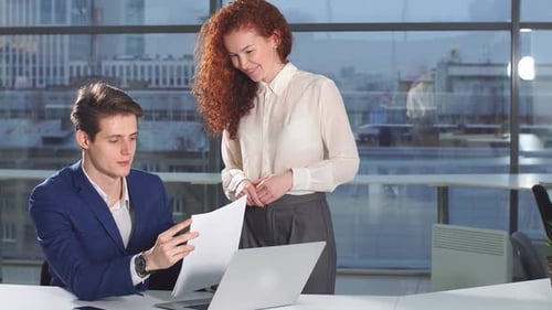 Young Office Colleagues Work with Paper Documents Discussing a New Strategy