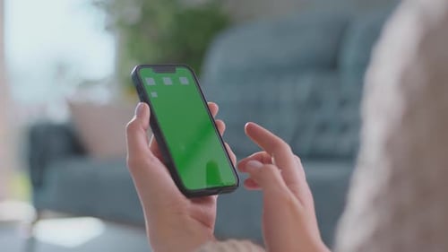 Smartphone with Green Screen Held and Used Indoors