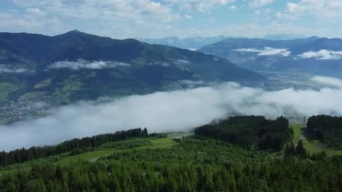 Flying over a valley in the Alps with low hanging clouds above the village below.
