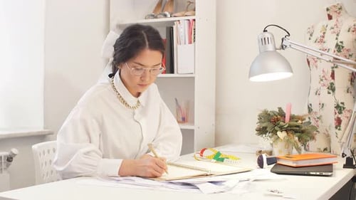 Beautiful Tailor Designer Writing in Notebook