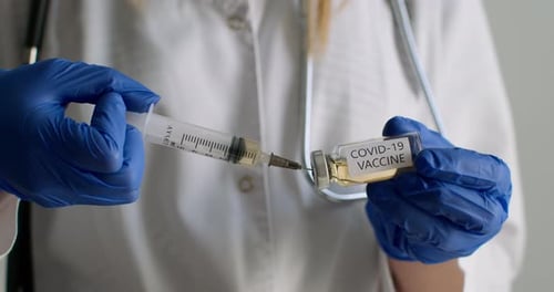 Close-up Shot. A Lab Worker Is Dialing the COVID-19 Vaccine Into a Syringe. Experiments in the