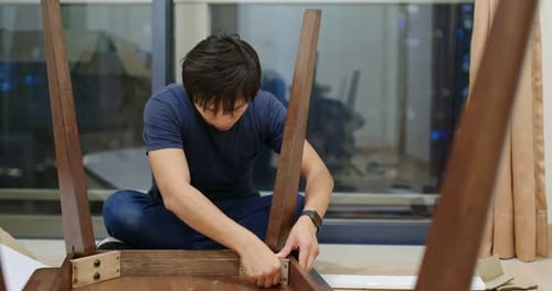 Young Adult Assembling Modern Table in Apartment at Night