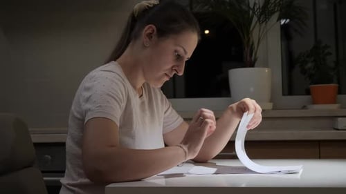 Woman Reads Papers at Table at Night