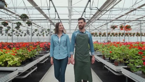 Botanist Couple Walking Through Greenhouse Full of Flowers