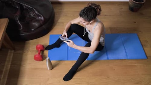 Woman Relaxing After Workout Using Mobile Device