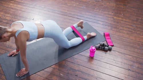 Female Does Plank with Exercise Band on Yoga Mat