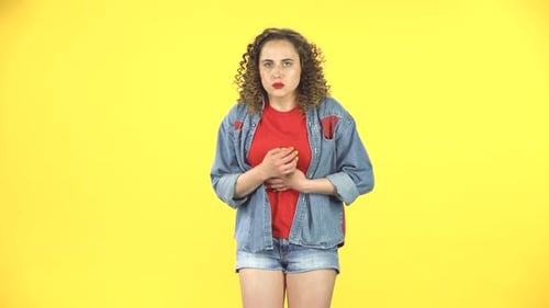 Linda mujer se siente mal, le duele el estómago, siente náuseas sobre fondo amarillo en el estudio