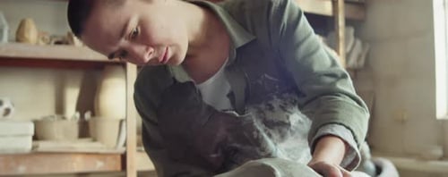 Female Sculptor Working on Clay Head in Workshop