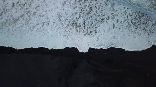 Waves coming up onto the black sand beach near Vik in Iceland from drone