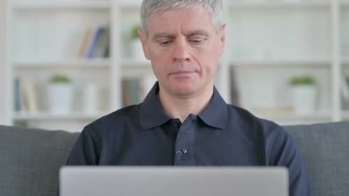 Mature Man Using Laptop and Smiling Indoors