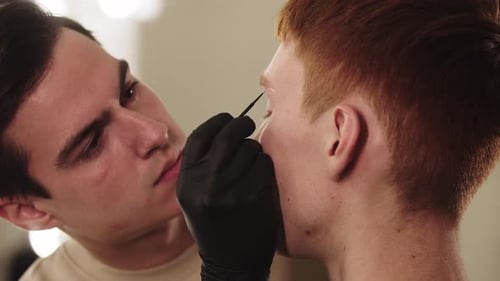 An Eyebrow Master Working with Brows of His Male Client
