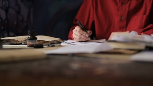 Person Writing with Pen and Ink at Desk