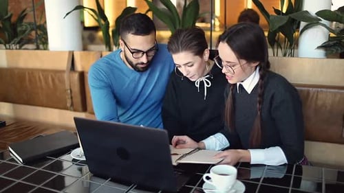 Three Adults Collaborating on Project in a Cafe