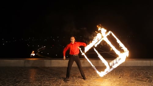 Performer Spins Burning Cube Prop at Night