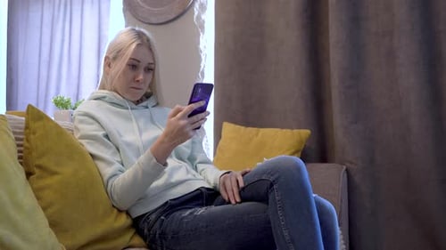 Woman Using Smartphone While Relaxing on Couch