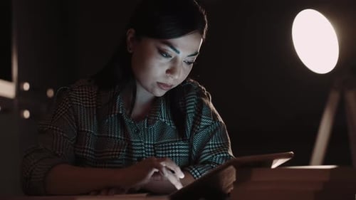 Woman Working Late at Desk with Tablet