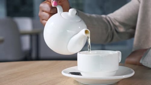 AfricanAmerican Lady Pours Hot Water Into Cup in Cozy Cafe