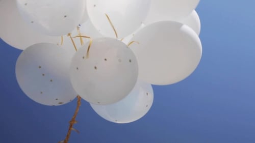 Floating White Balloons Against Blue Sky