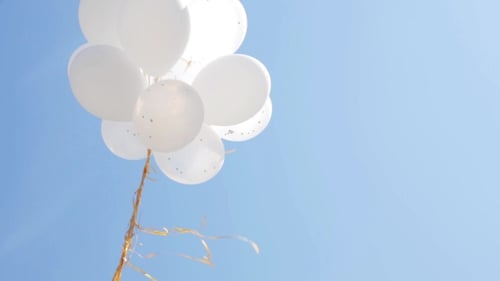 White Balloons Floating against Blue Sky