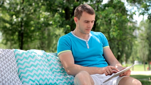 Man Relaxing on a Bench Using Digital Tablet