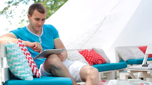 Man Using Tablet Device Outside On Comfortable Furniture