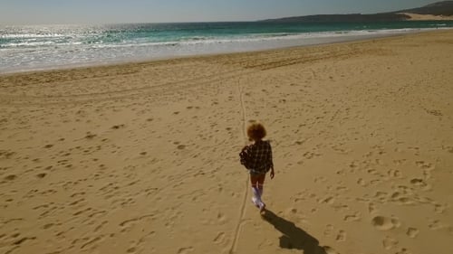 Young Woman Walking Alone Along a Beach