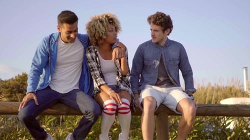 Three Friends Sit Together Talking on Fence