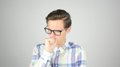 Young Man Coughing in Front of Plain Background