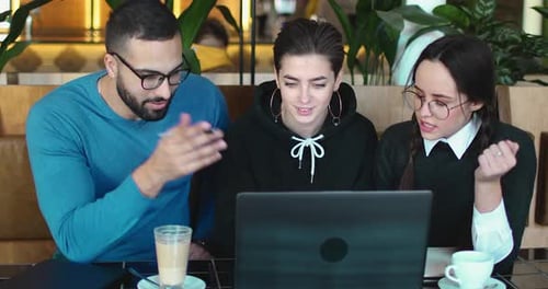 Team Collaborating on Laptop in Urban Cafe