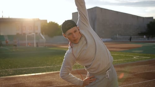 Man Stretching on Running Track at Sunrise