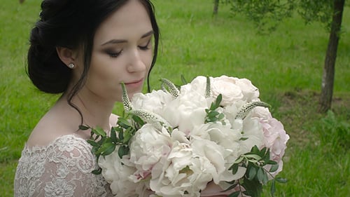 Attractive Woman in Wedding Dress Smelling Bouquet